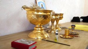 მღვდელი ასრულებს ბინის კურთხევის რიტუალს სანთლებით და ხატებით