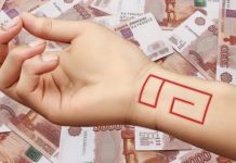 ენერგეტიკული ნაკადი, რომელიც სურვილების შესრულებაში და გეხმარება Forearm with a red geometric outline (rectangular shapes) drawn or tattooed, resting over a spread of banknotes in the background.